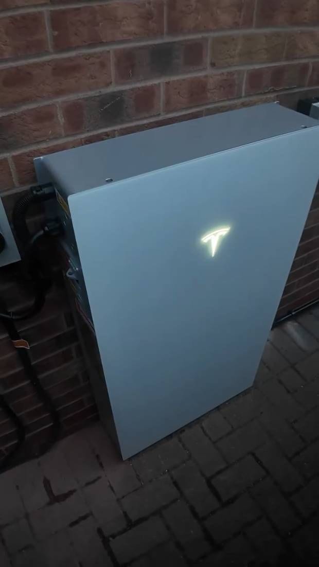 The cable side of a home battery fitted to an outside brick wall