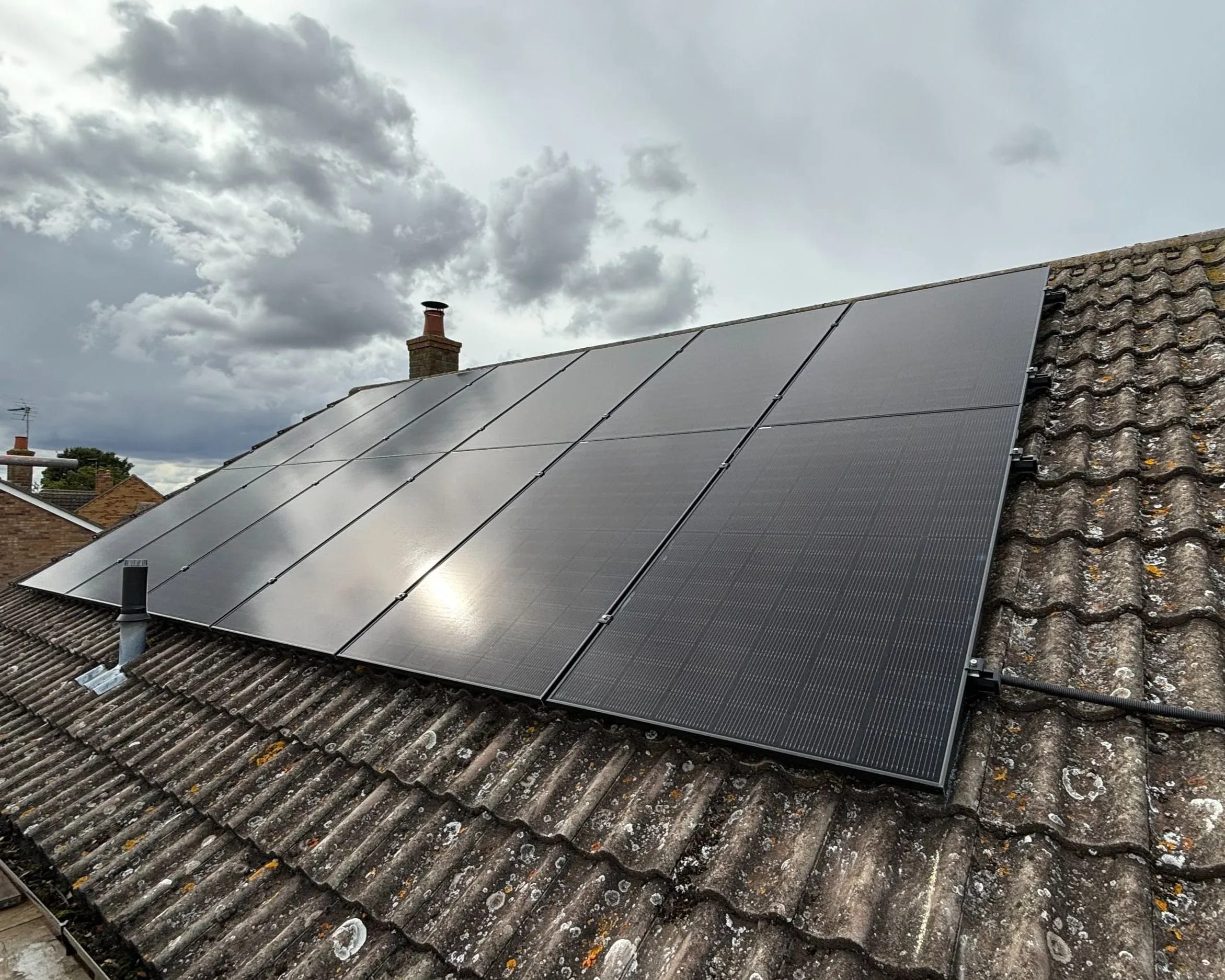 Black panels on a concrete-tile roof under a grey sky